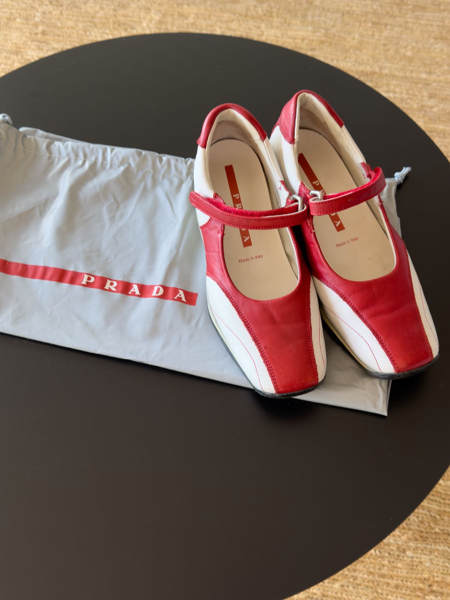 Prada Mary Jane style sneakers in red and white, placed on a Prada dust bag, representing the Vieux Riche Vintage Collection.