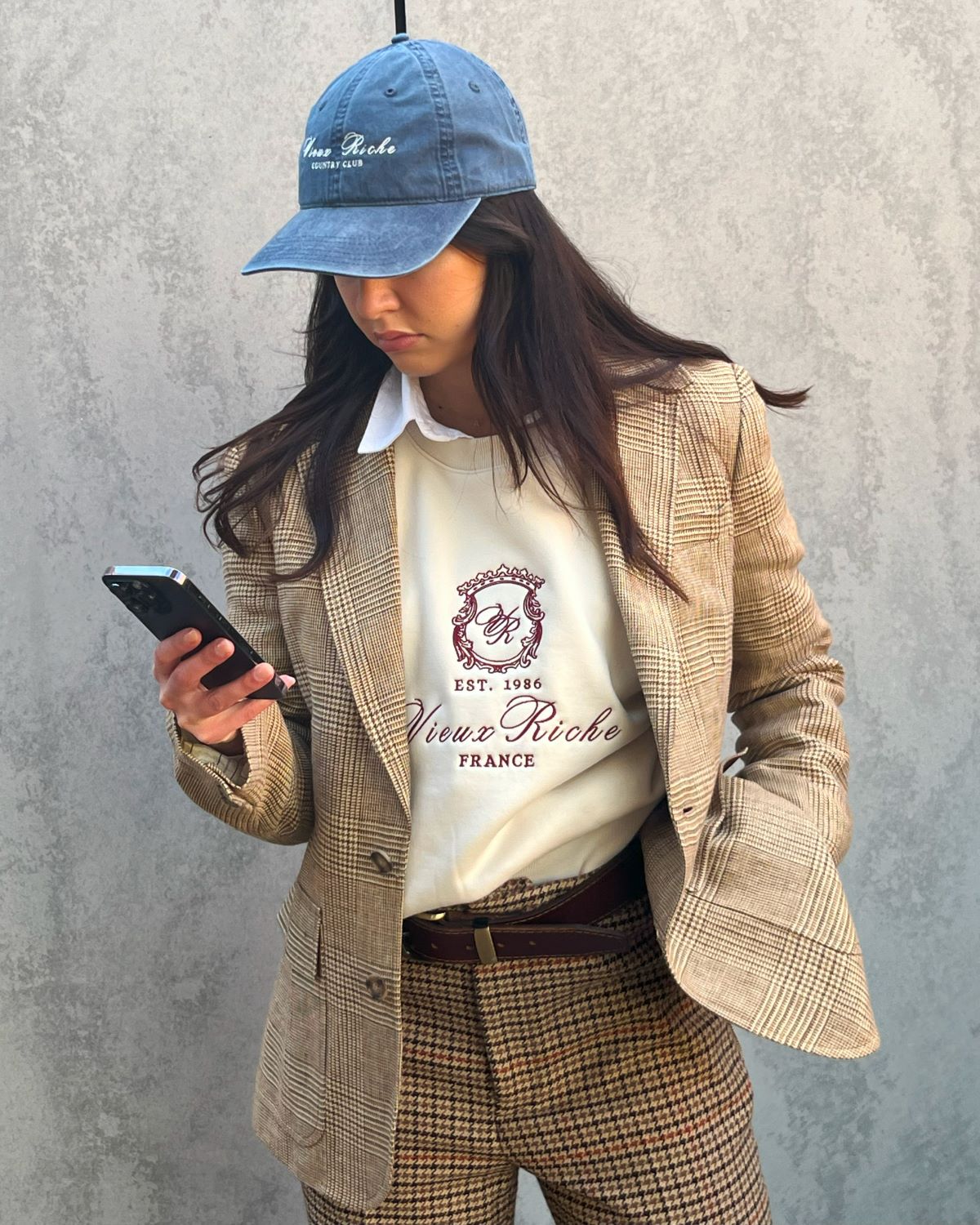 Woman wearing Vieux Riche Country Club Classic cap in vintage blue, a woollen ralph lauren blazer, and Vieux Riche sweatshirt, epitomising the Country Club Collection.