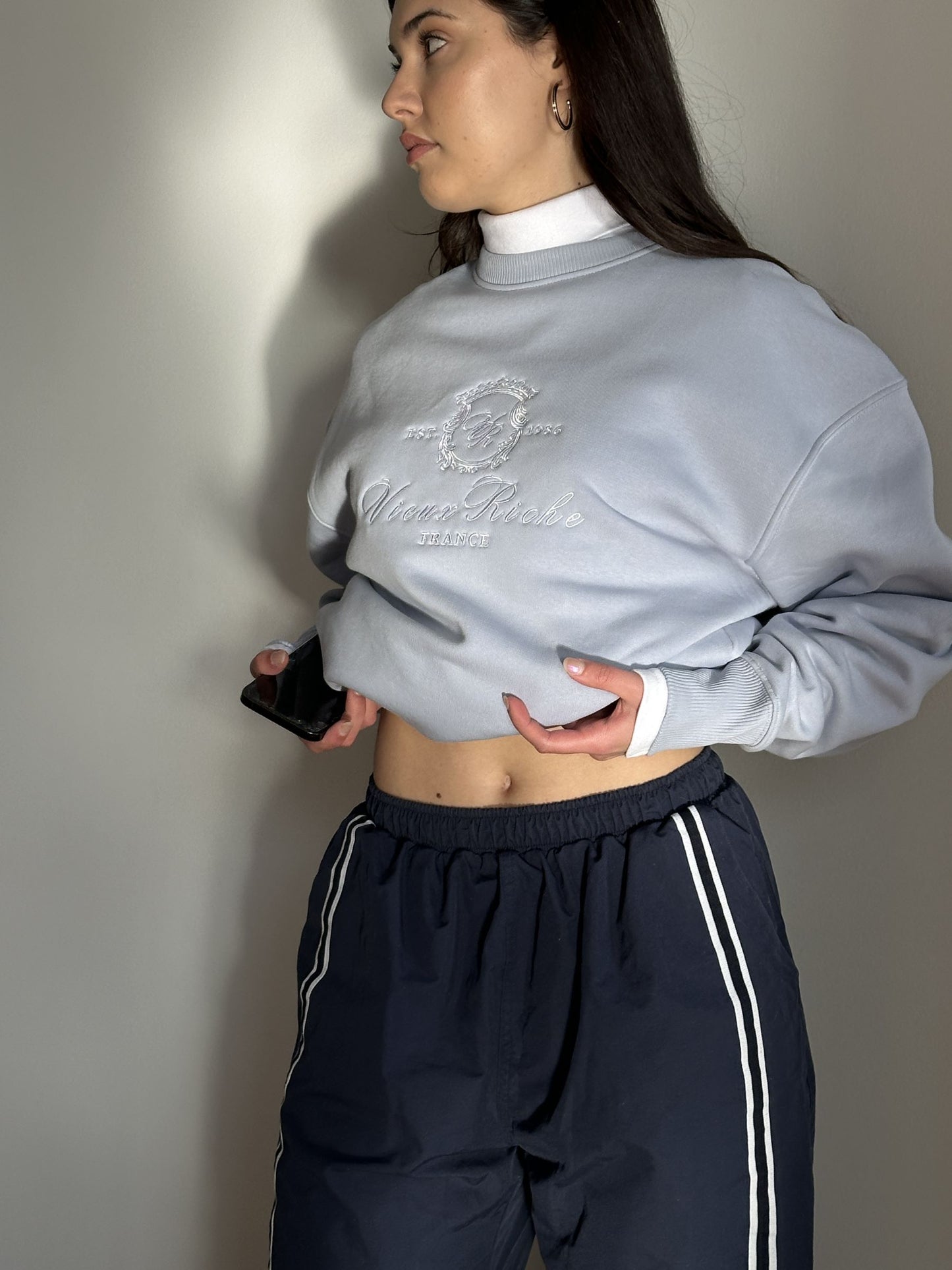 Woman wearing Vieux Riche Leisure League crew neck sweatshirt in dolphin blue with navy blue pants.