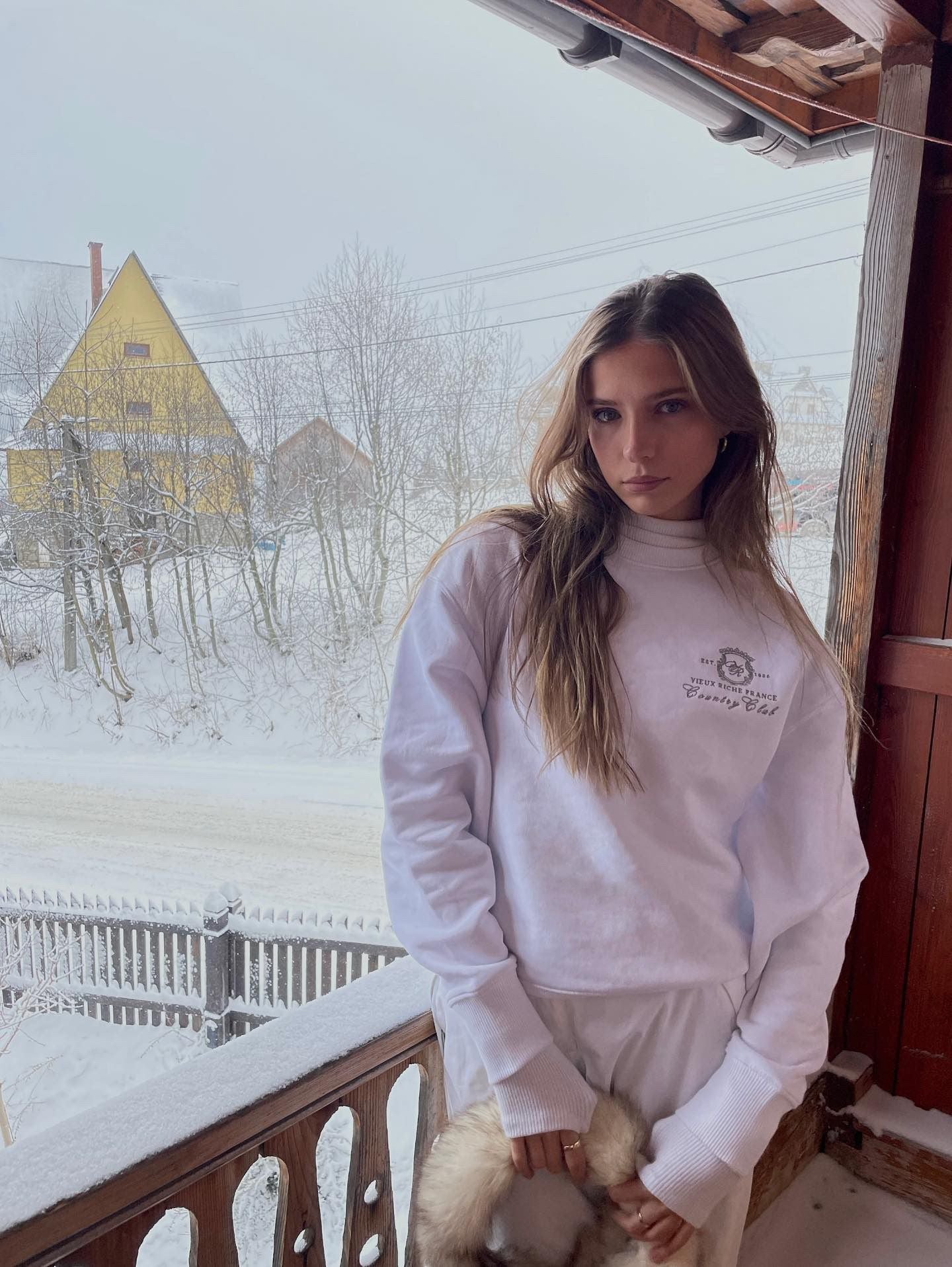 Woman in the snow, wearing the Court Couture Blanc Crew in old money style.