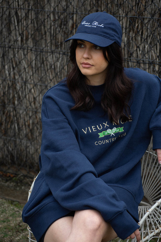 Woman wearing the Navy Country Club Classic Cap with matching crew neck sweatshirt, epitomizing the old money aesthetic.