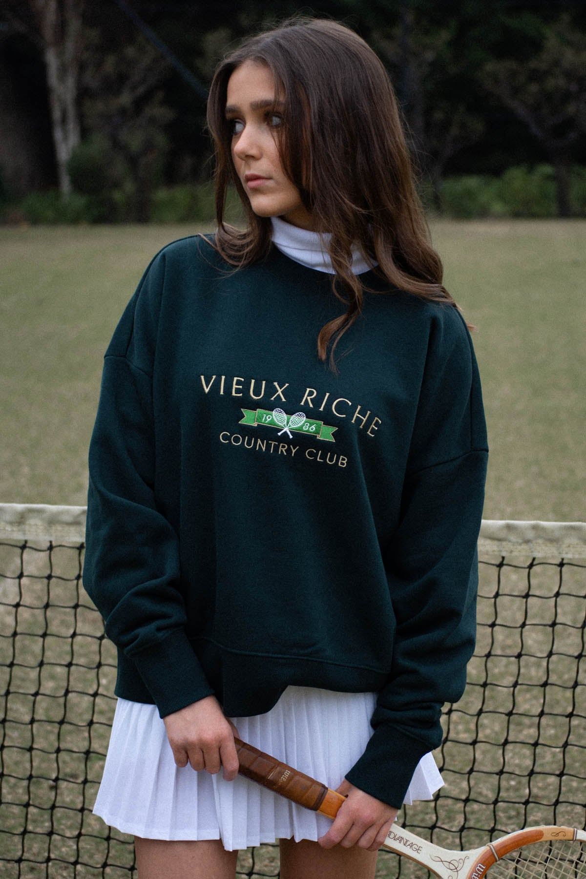 Woman in Pine Green Vintage Country Club Crew, poised on a tennis court, reflecting the classic old money look.